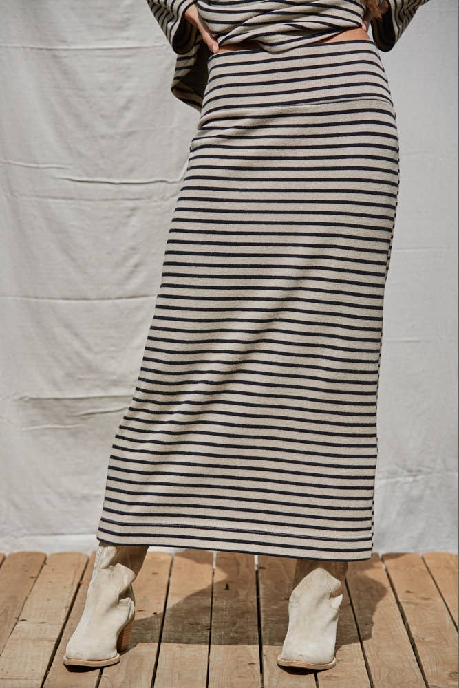 Person wearing a long black and white striped dress with white boots on a wooden floor.