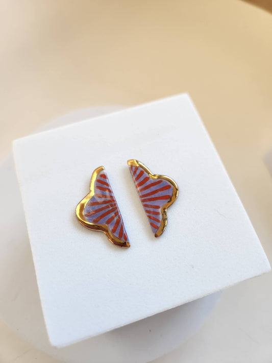 Butterfly-shaped earrings on a white stand with a beige background