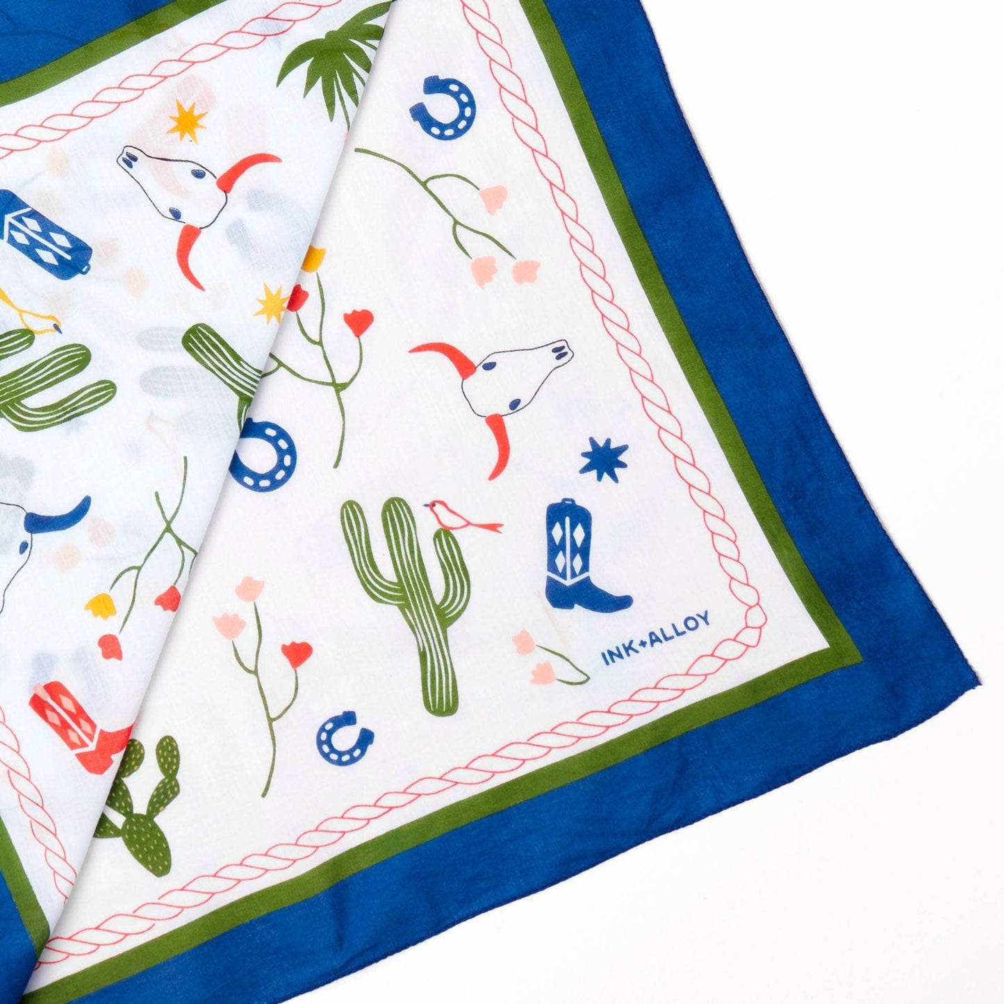 Fabric with desert-themed patterns including cacti, boots, and horses on a white background.