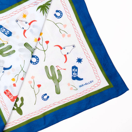 Fabric with desert-themed patterns including cacti, boots, and horses on a white background.