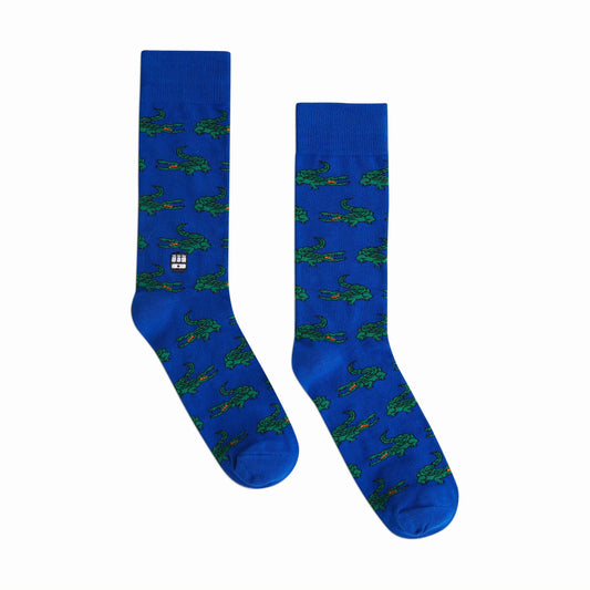 Pair of blue socks with green alligator pattern on a white background