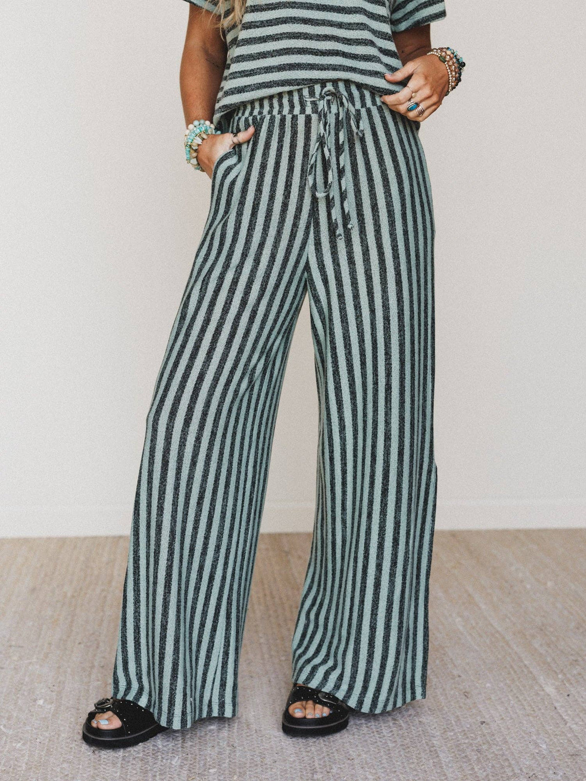 Person wearing green and white striped pants with a plain background