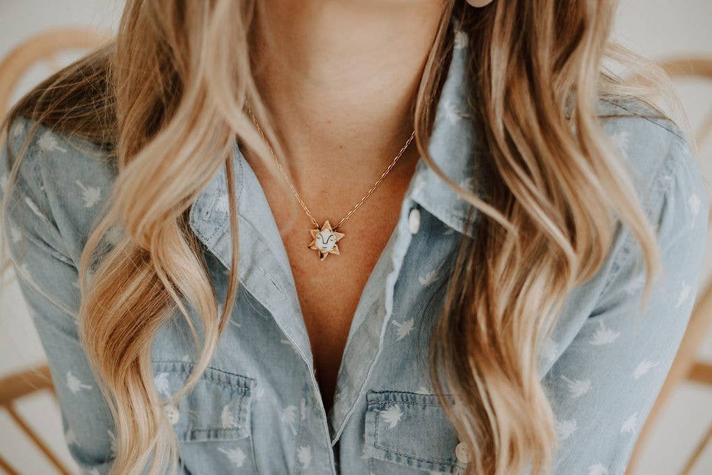 Person wearing a star-shaped necklace with a denim shirt
