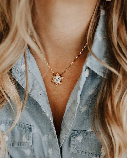 Person wearing a star-shaped necklace with a denim shirt