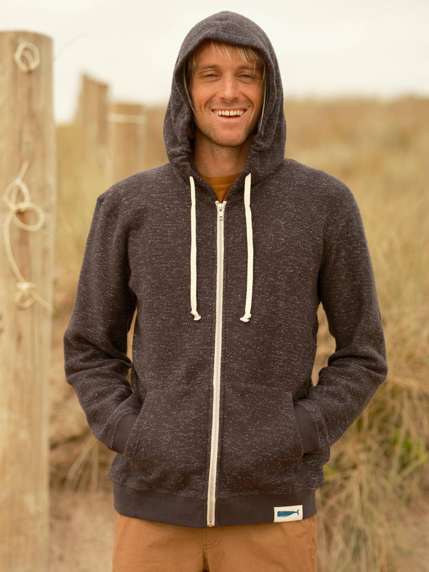Man wearing a dark hoodie with a visible brand logo outdoors.
