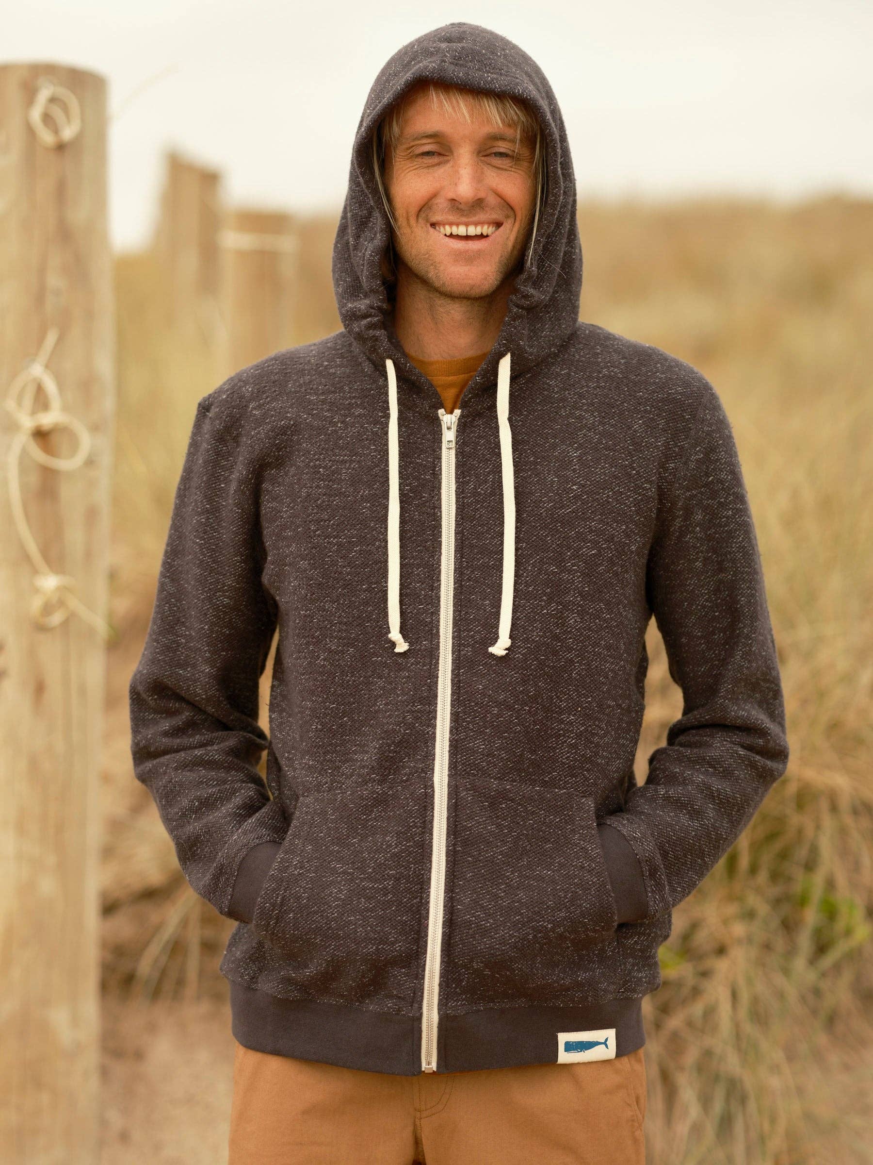 Man wearing a dark hoodie with a visible brand logo outdoors.