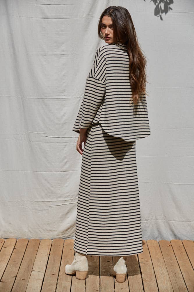 Woman wearing a long black and white striped dress against a plain background