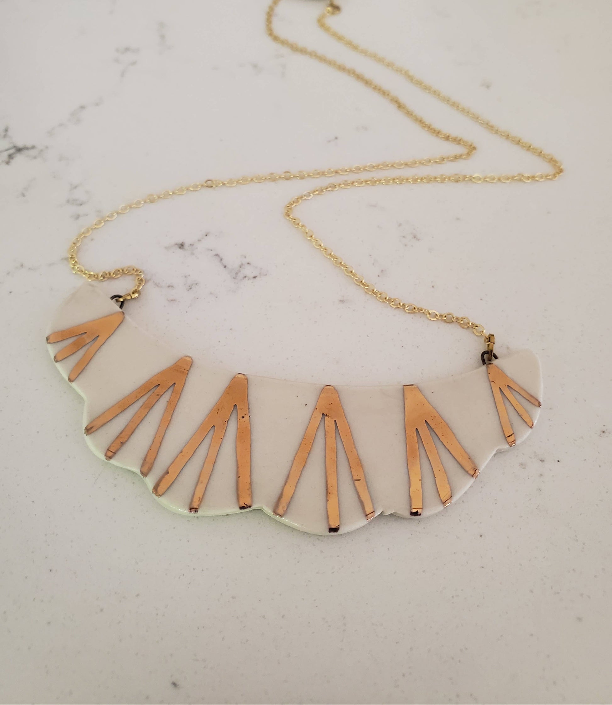 Necklace with geometric pendant on a marble surface