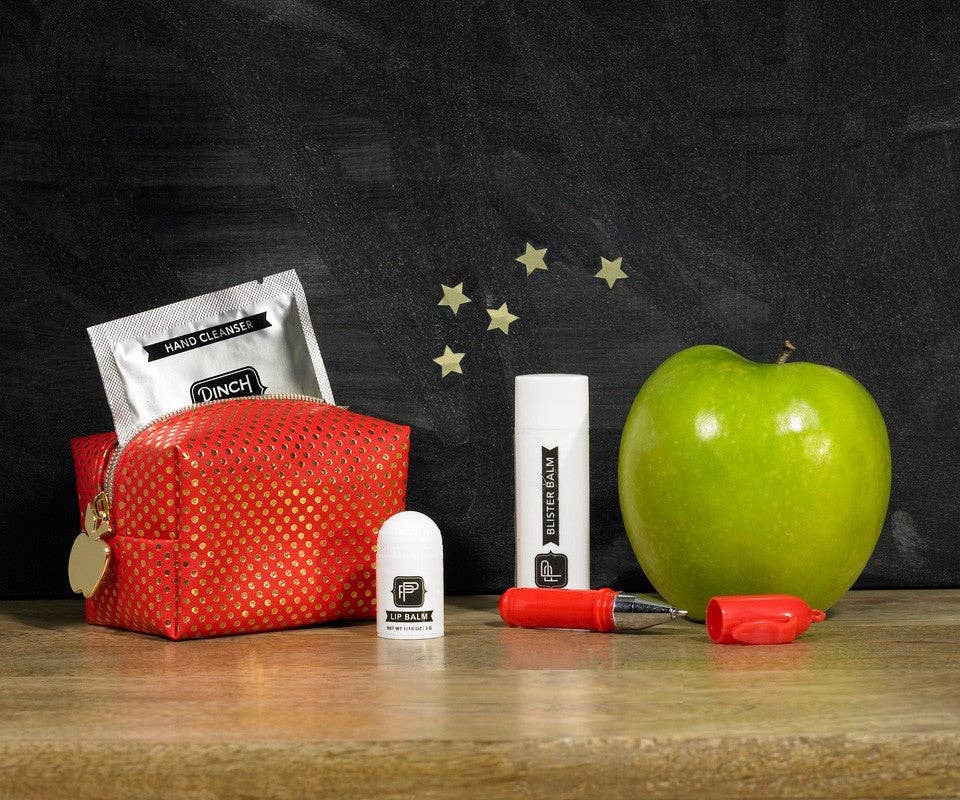 Red pouch, green apple, and small containers on a wooden surface with a chalkboard background.