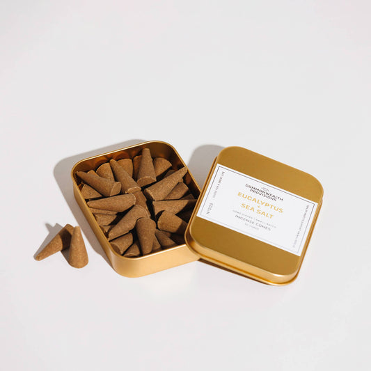 Gold tin with incense cones and a label on a white background