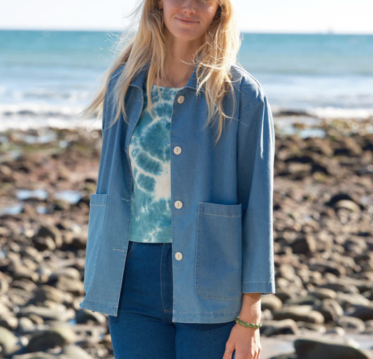 Women standing on the beach with a denim jacket, jeans and a blue and white tie-dye shirt.