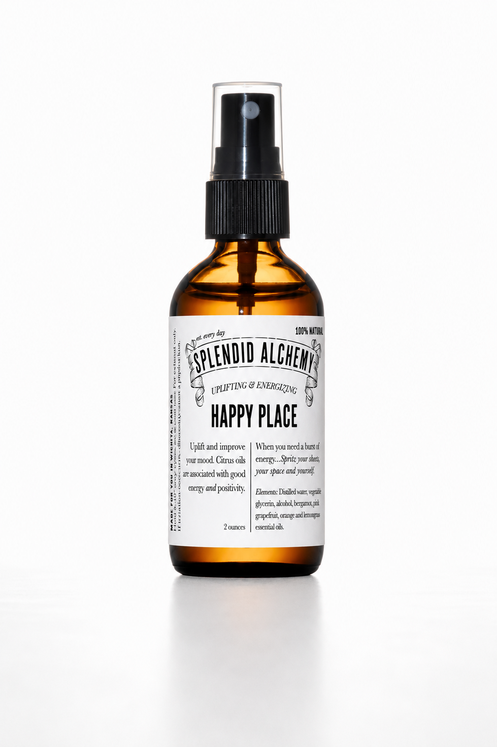 An amber glass spray bottle with a black pump dispenser and a white label reading 'Splendid Alchemy Happy Place' on a clean white background.