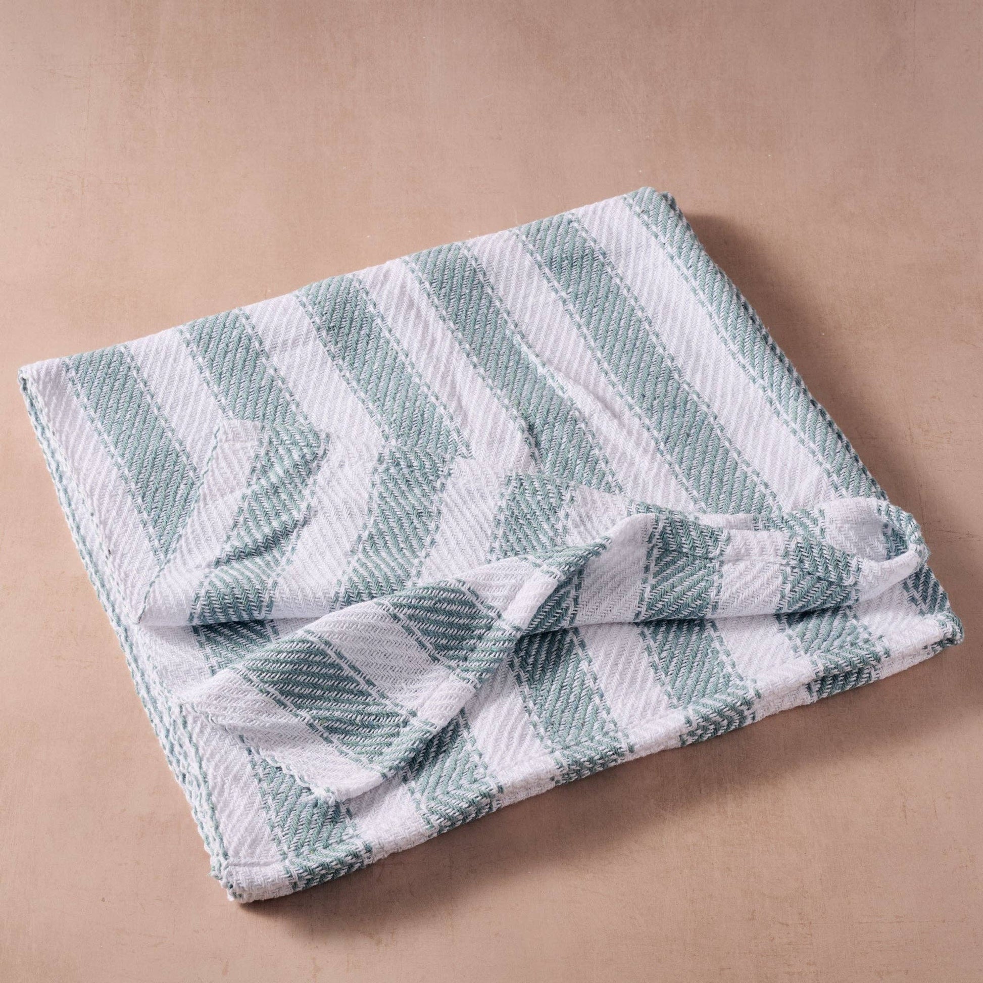 Folded green and white checkered towel on a beige background