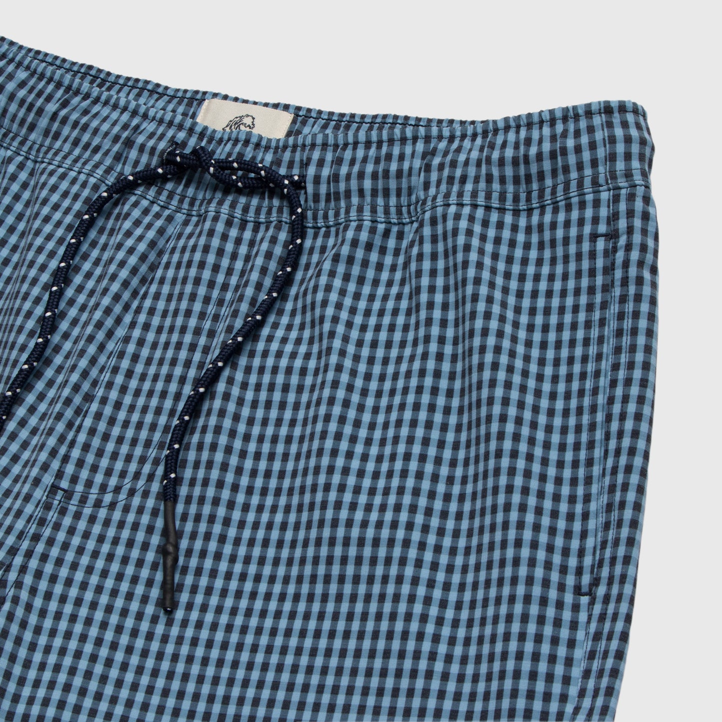 Blue and black checkered shorts with drawstring on a light gray background