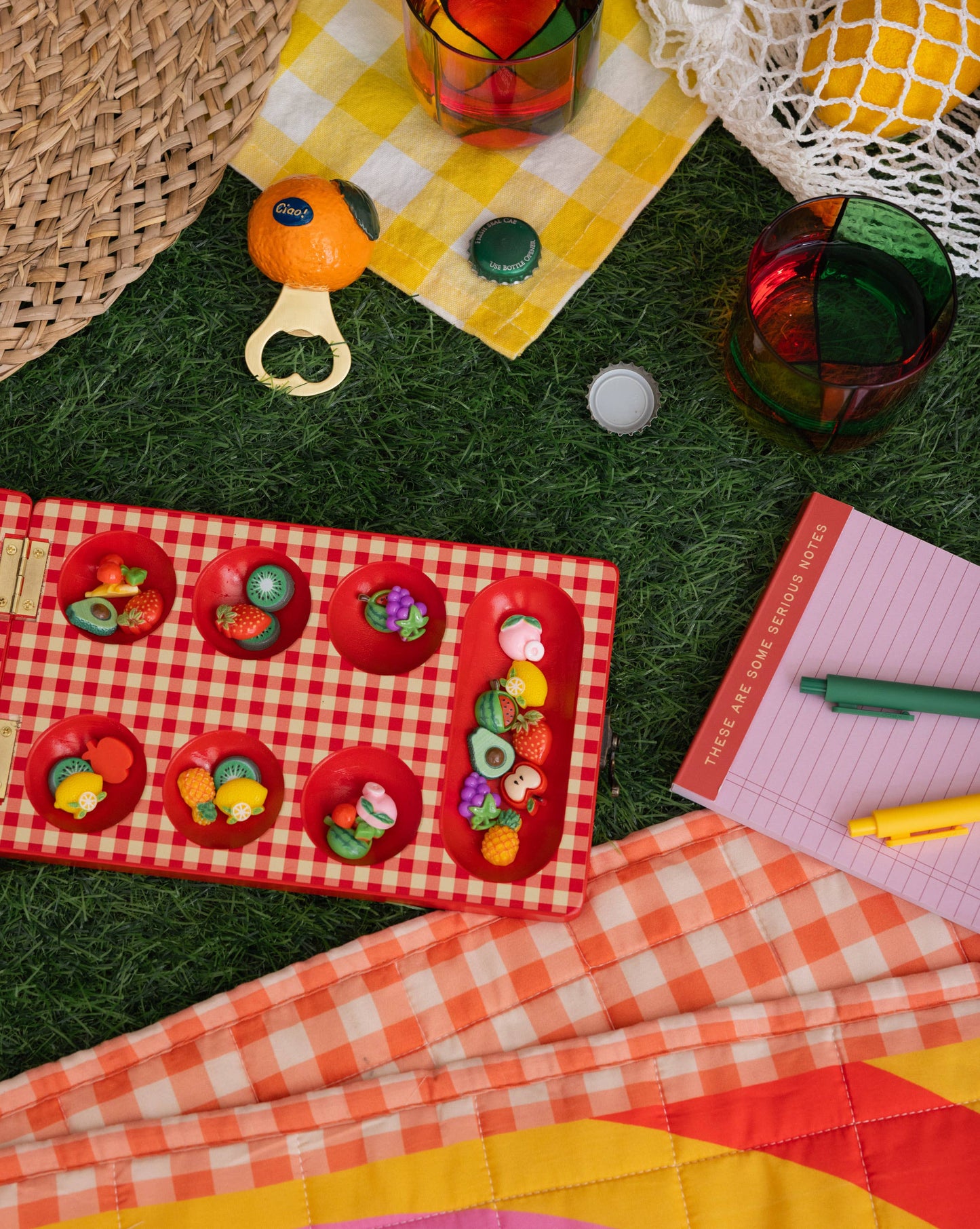 Colorful items on a checkered blanket with grass and woven surface