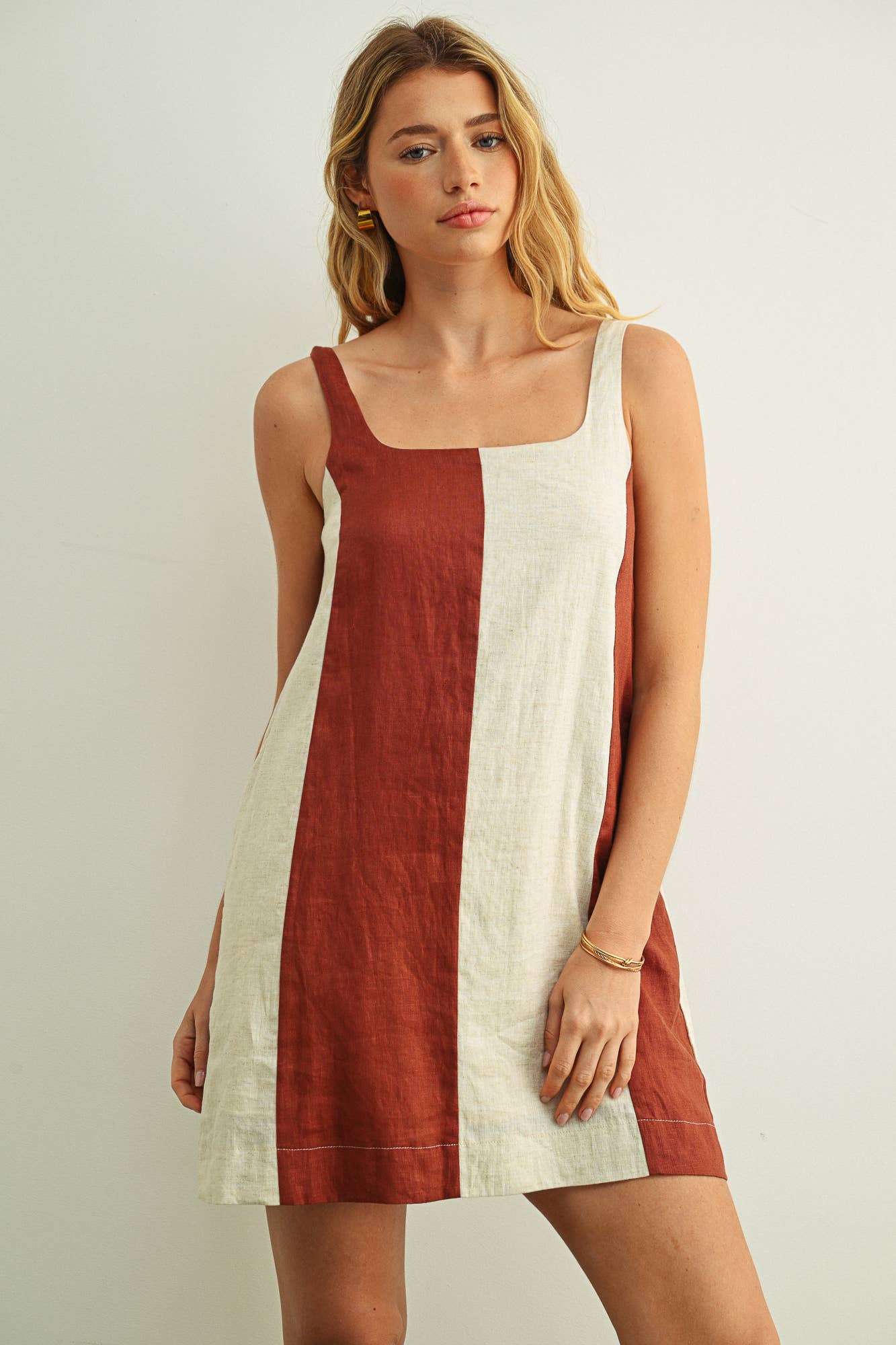 Woman wearing a sleeveless dress with a two-tone design on a plain background