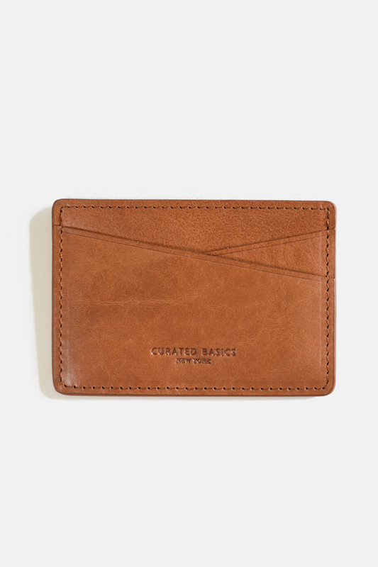 Brown leather cardholder with 'Curated Basics' branding on a white background