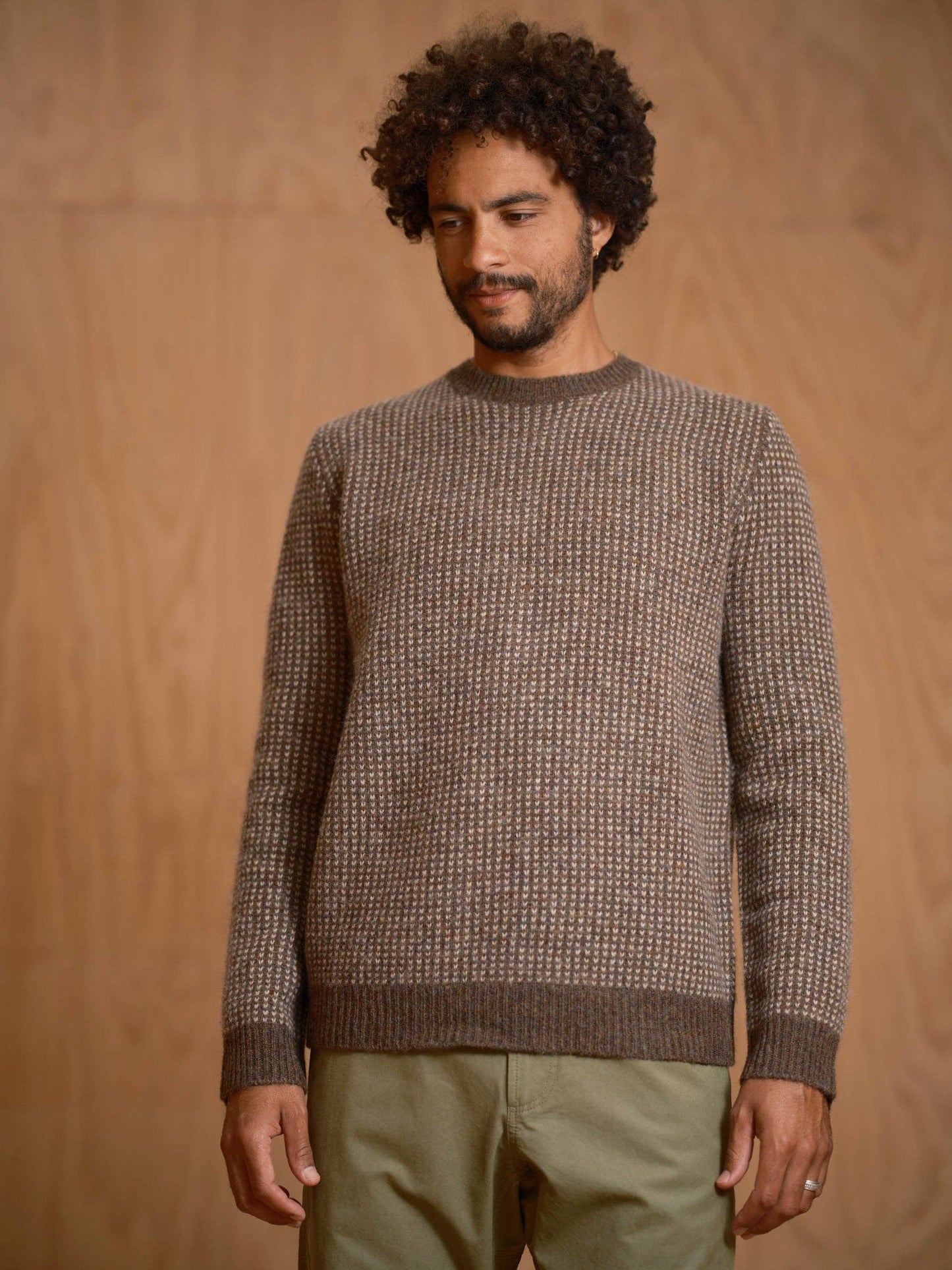 Man wearing a brown textured sweater against a wooden background