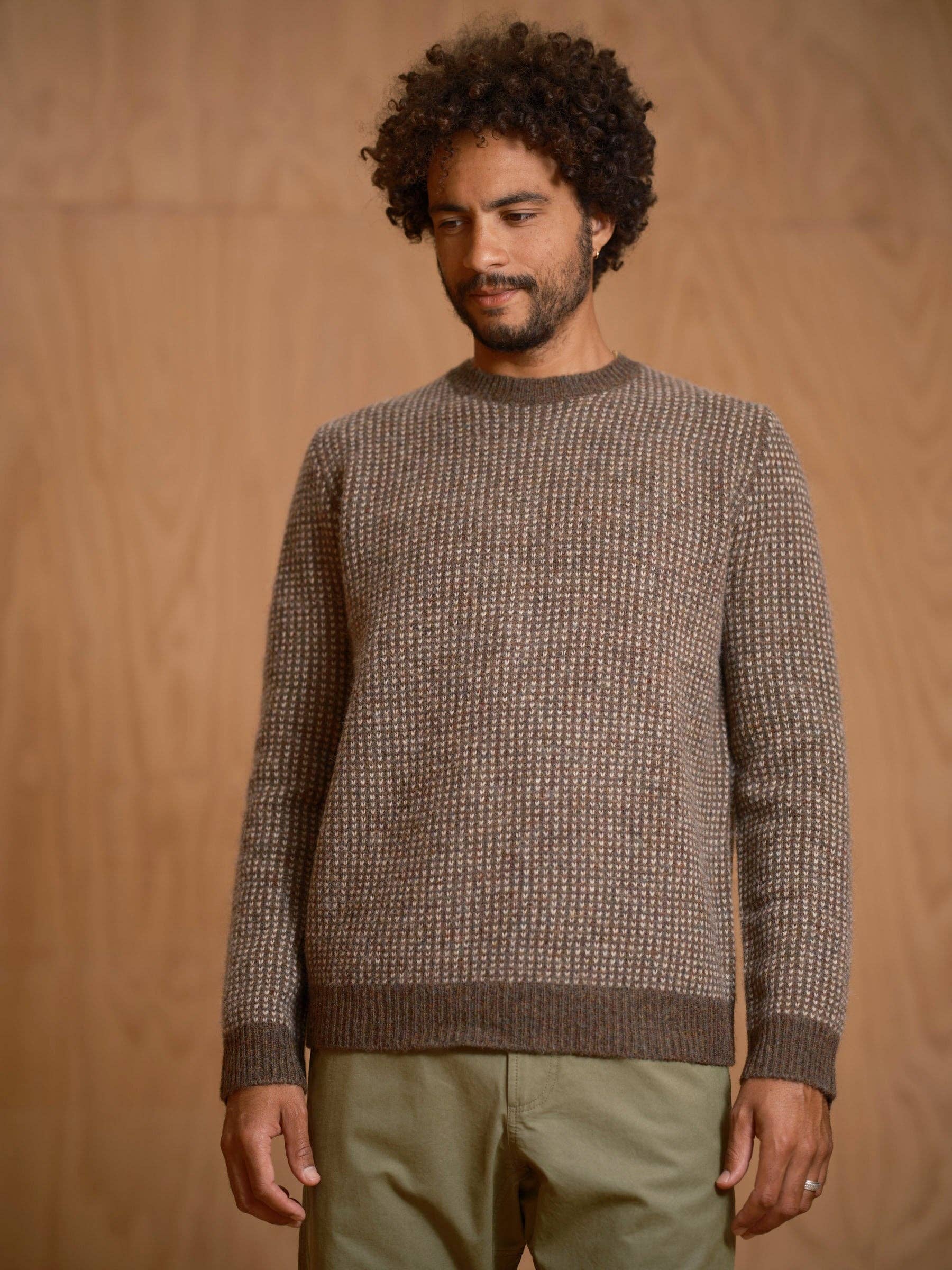 Man wearing a brown textured sweater against a wooden background