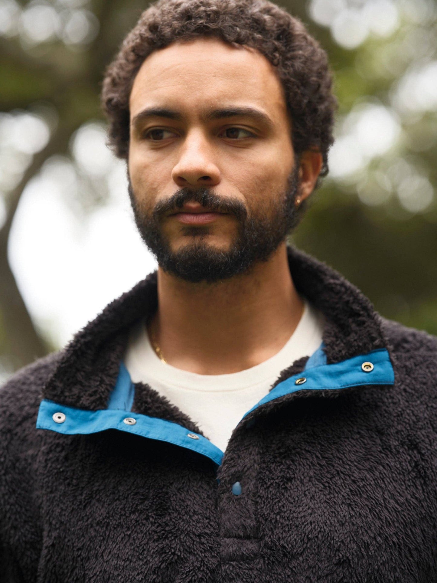 Man wearing a dark jacket with a blue collar outdoors