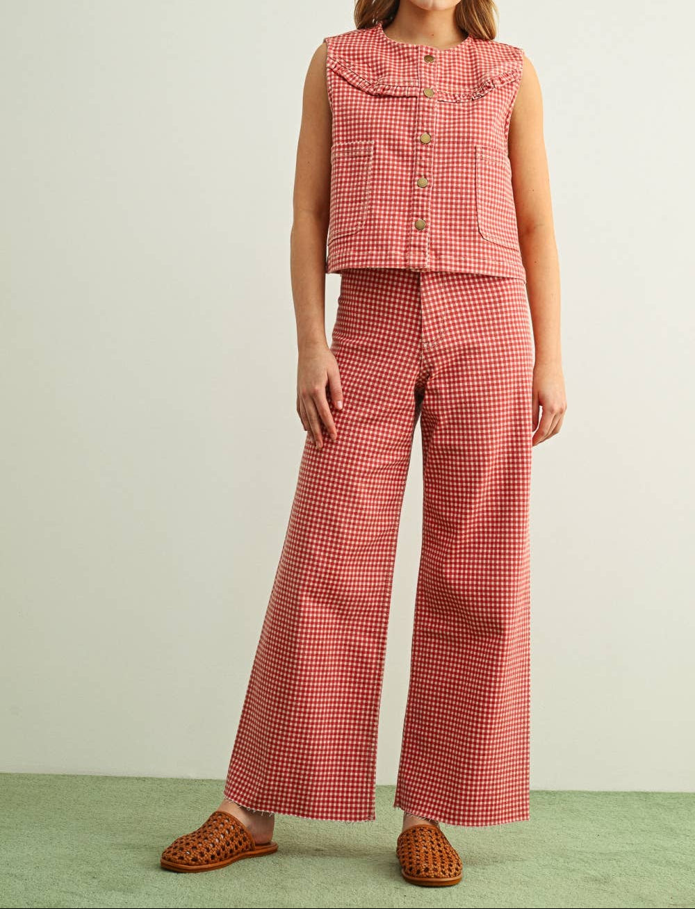 Woman wearing a red checkered sleeveless top and wide-leg pants against a light background
