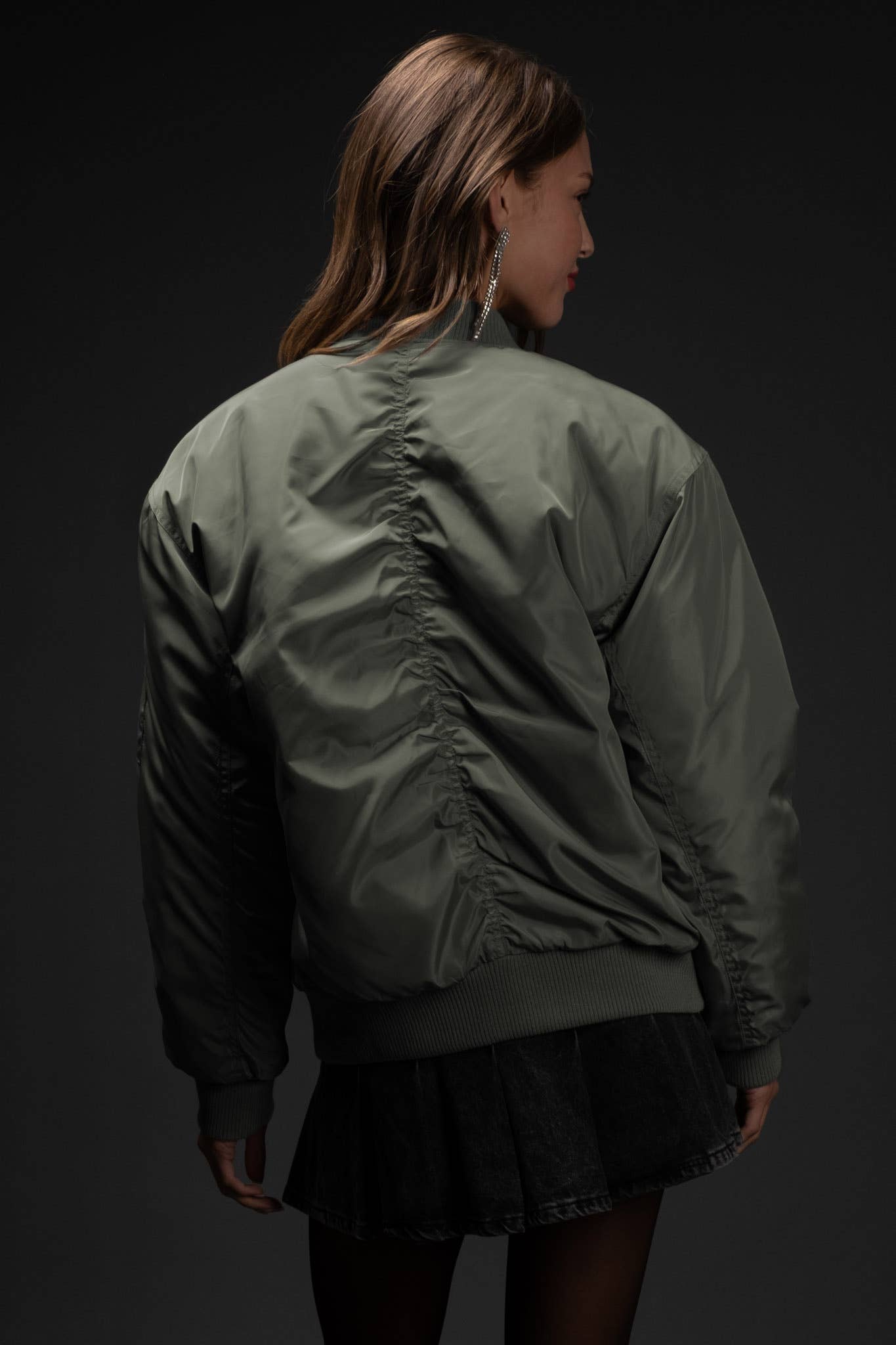 Person wearing a green bomber jacket on a black background