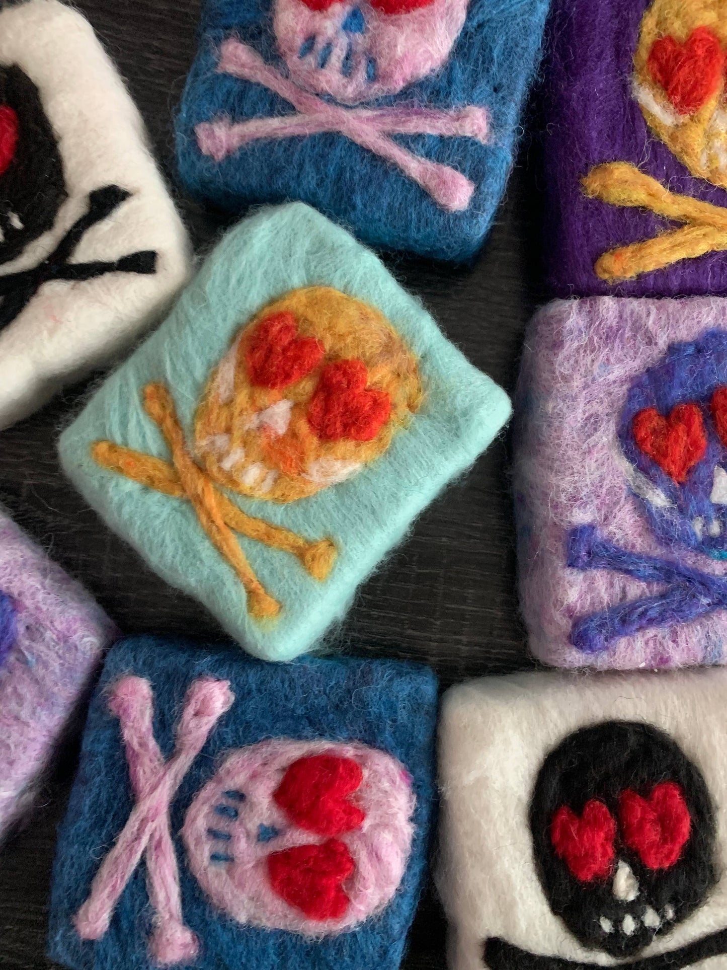 Collection of colorful felted pouches with skull and crossbones designs.