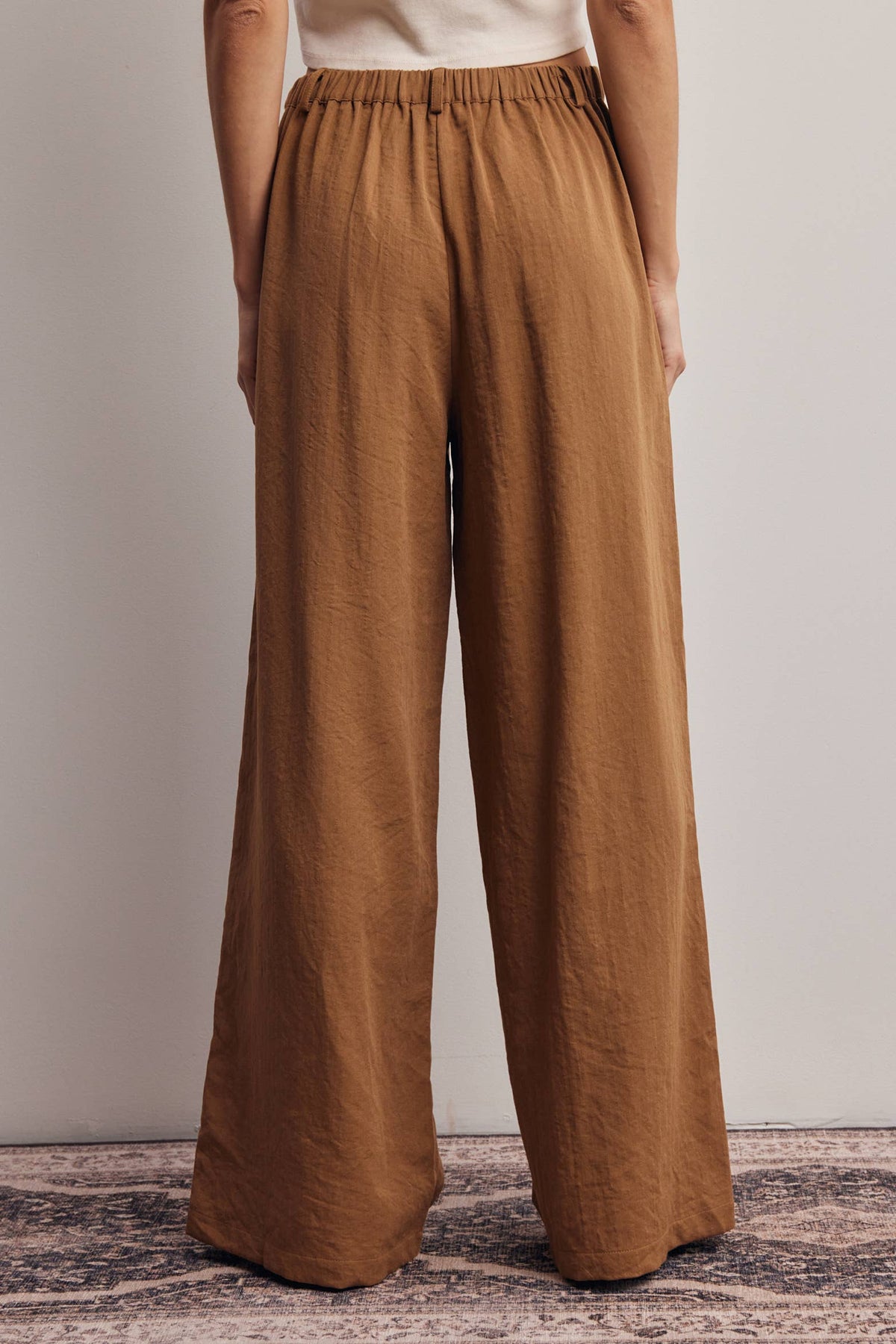 Brown wide-leg pants worn by a person on a neutral background