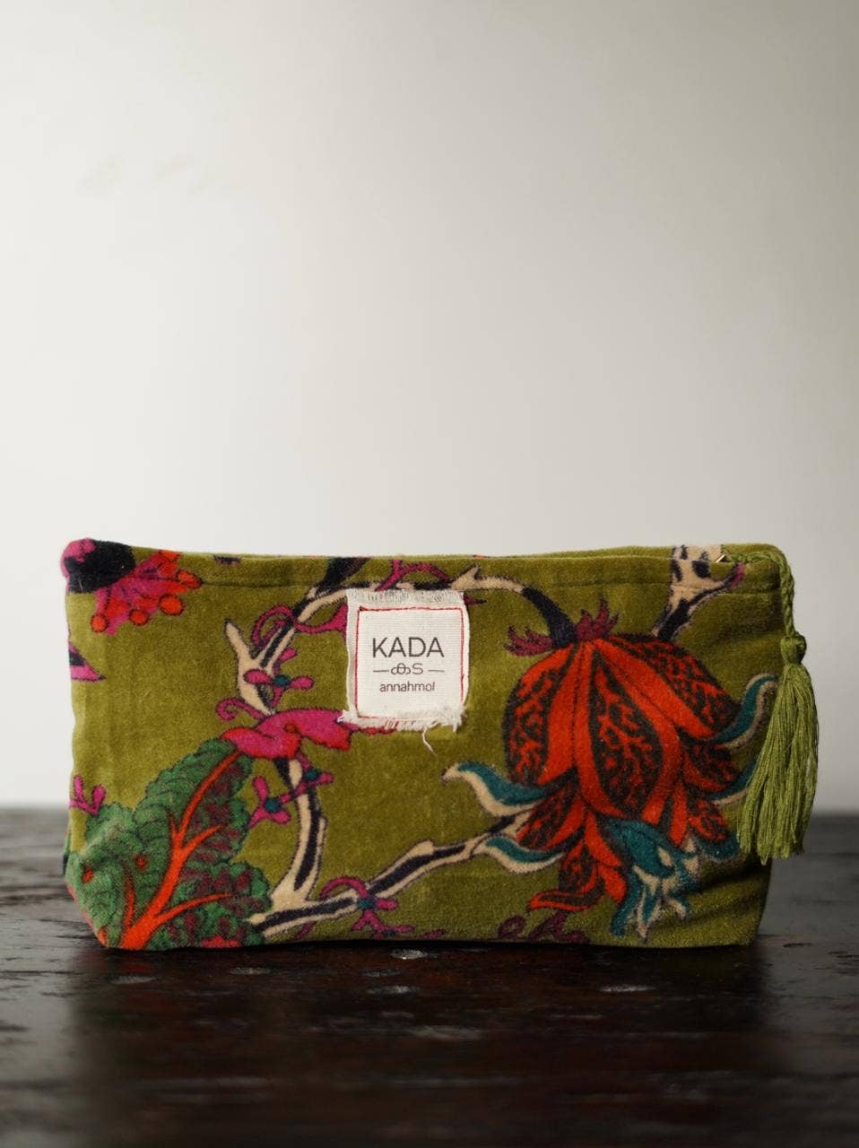 Floral patterned pouch with 'KADA' label on a wooden surface