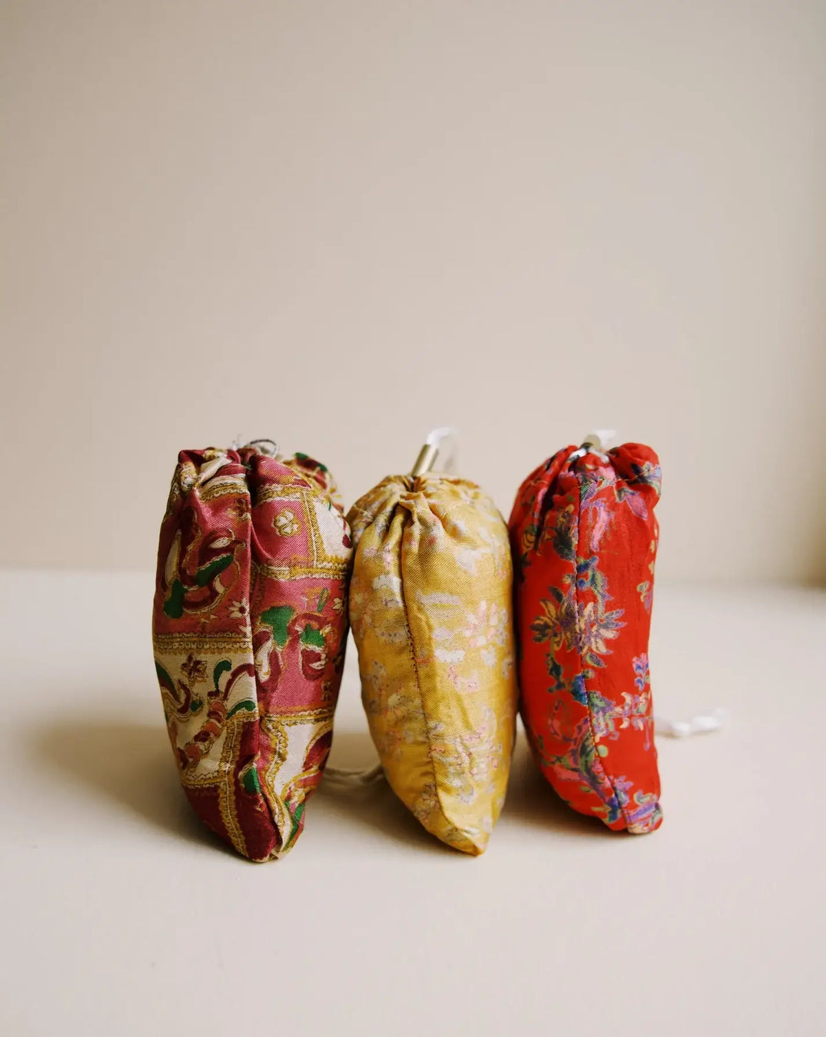 Three drawstring bags in floral patterns on a beige background