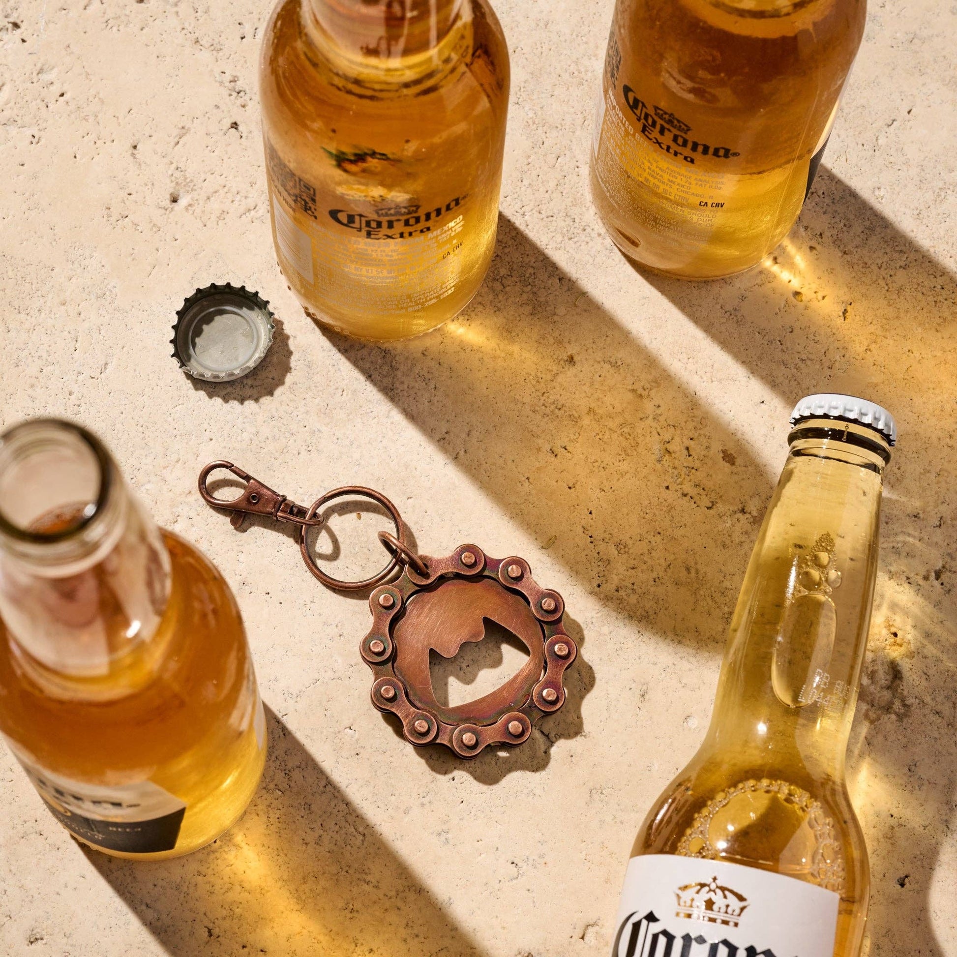 Four Corona beer bottles with a bottle opener on a textured surface