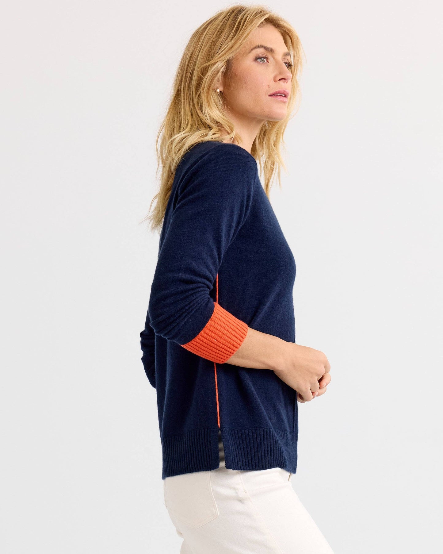 Woman wearing a navy sweater with orange accents on a white background