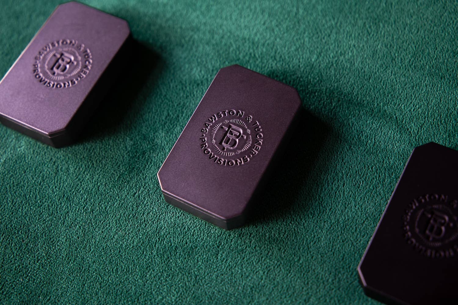 Three purple chocolate bars with a brand logo on a green surface