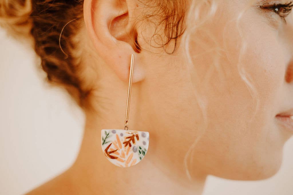 Close-up of a woman wearing floral earrings with a blurred background