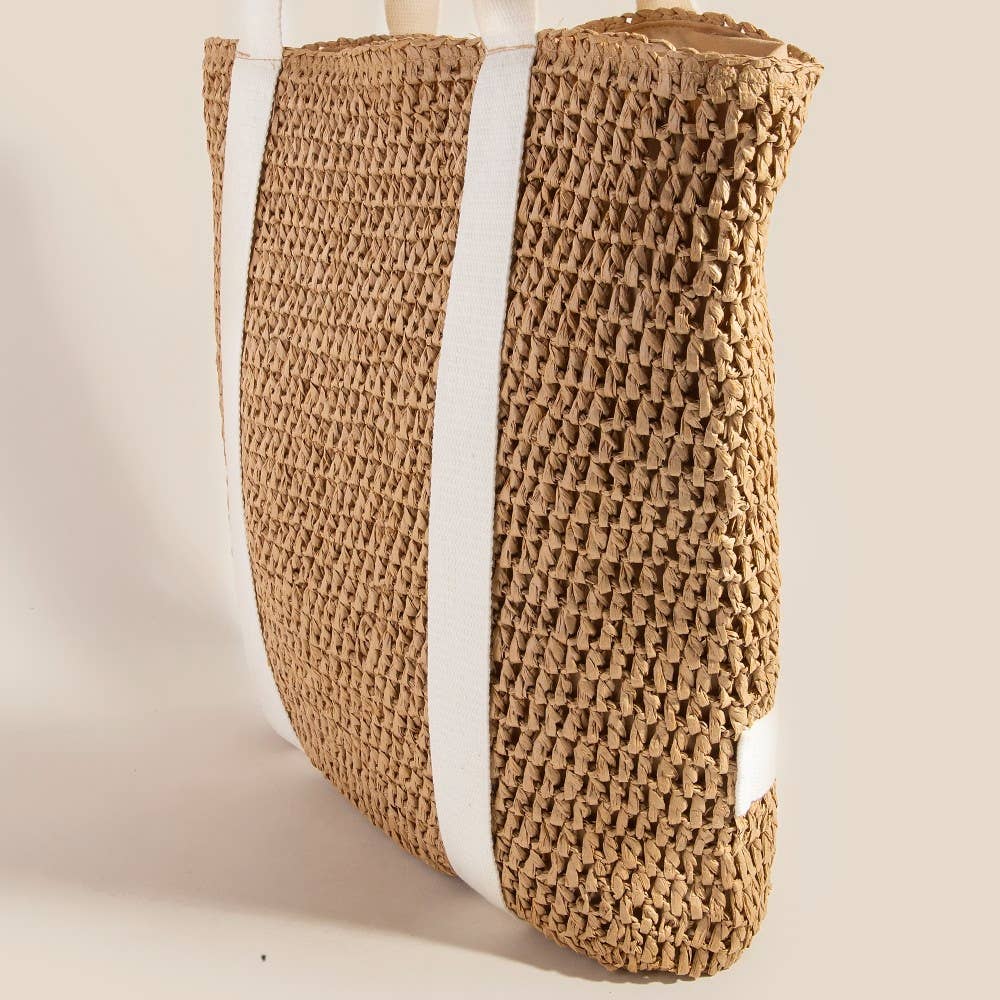 Woven straw bag with a white strap on a light beige background
