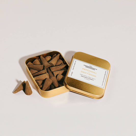 Open gold tin containing incense sticks with a visible label on a white background