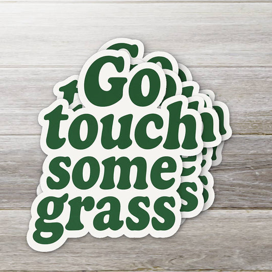 Stack of 'Go touch some grass' stickers on a wooden surface