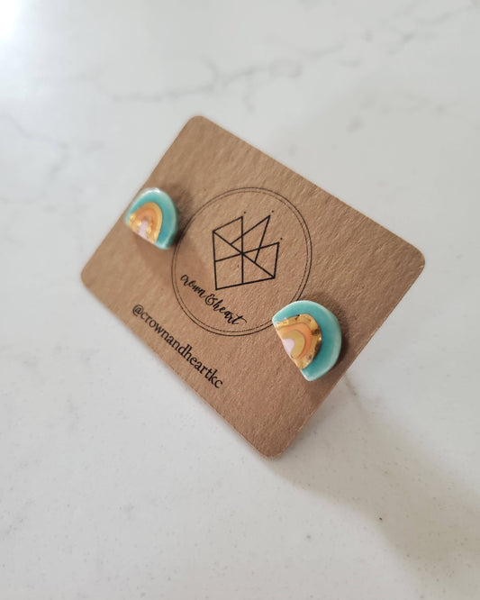 Pair of earrings on a branded card with a geometric design on a light background