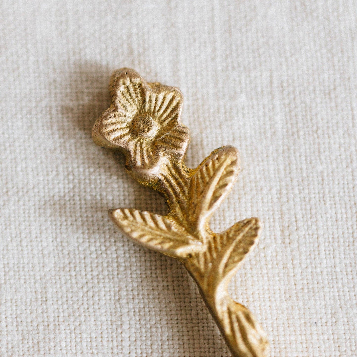 Gold decorative element with floral design on a beige fabric background