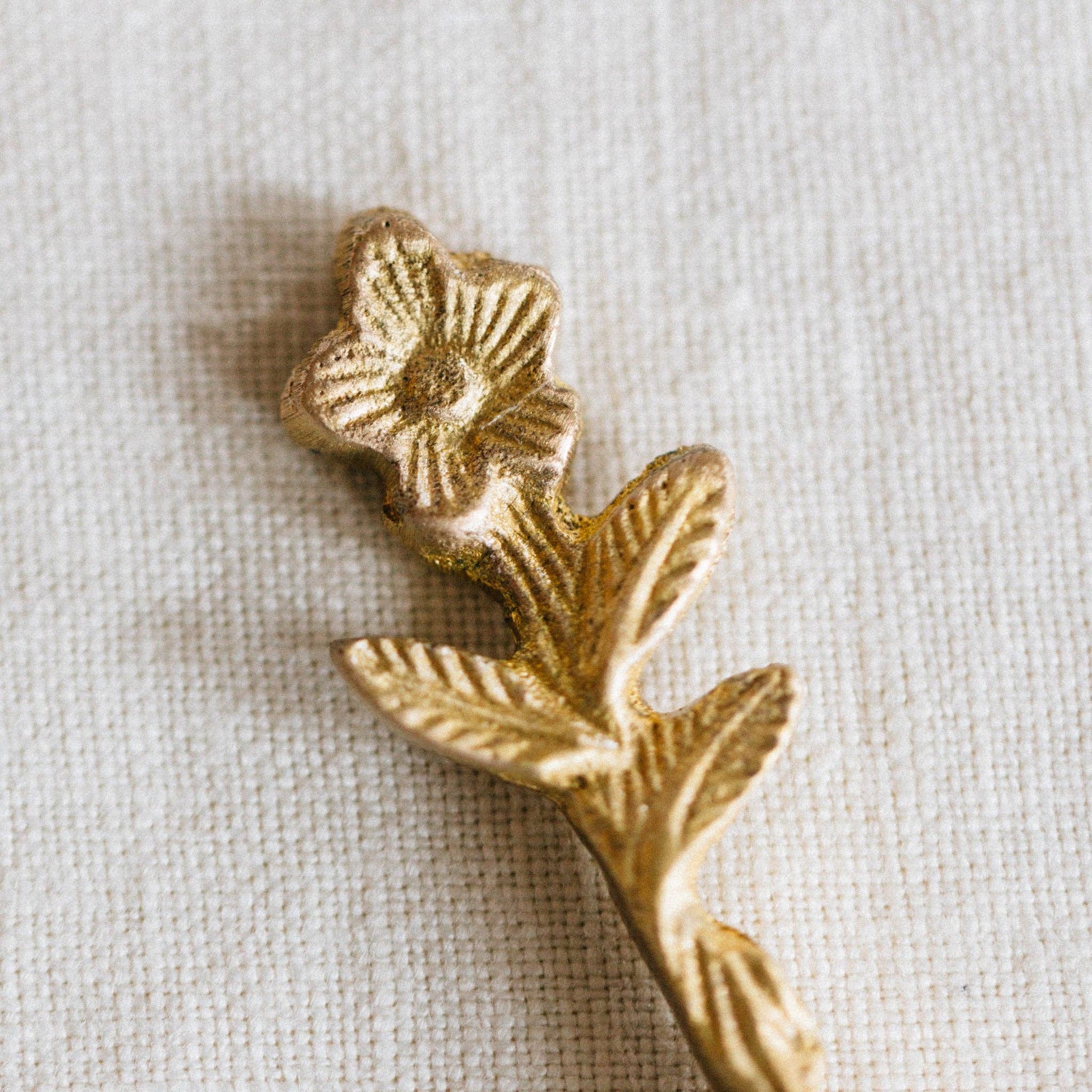 Gold decorative element with floral design on a beige fabric background