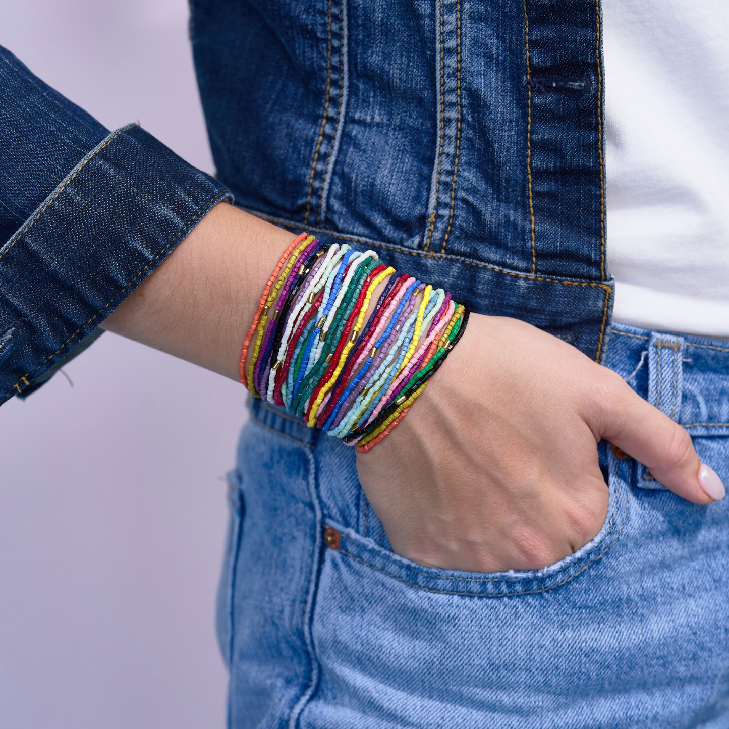 Person wearing a colorful bracelet on a plain background