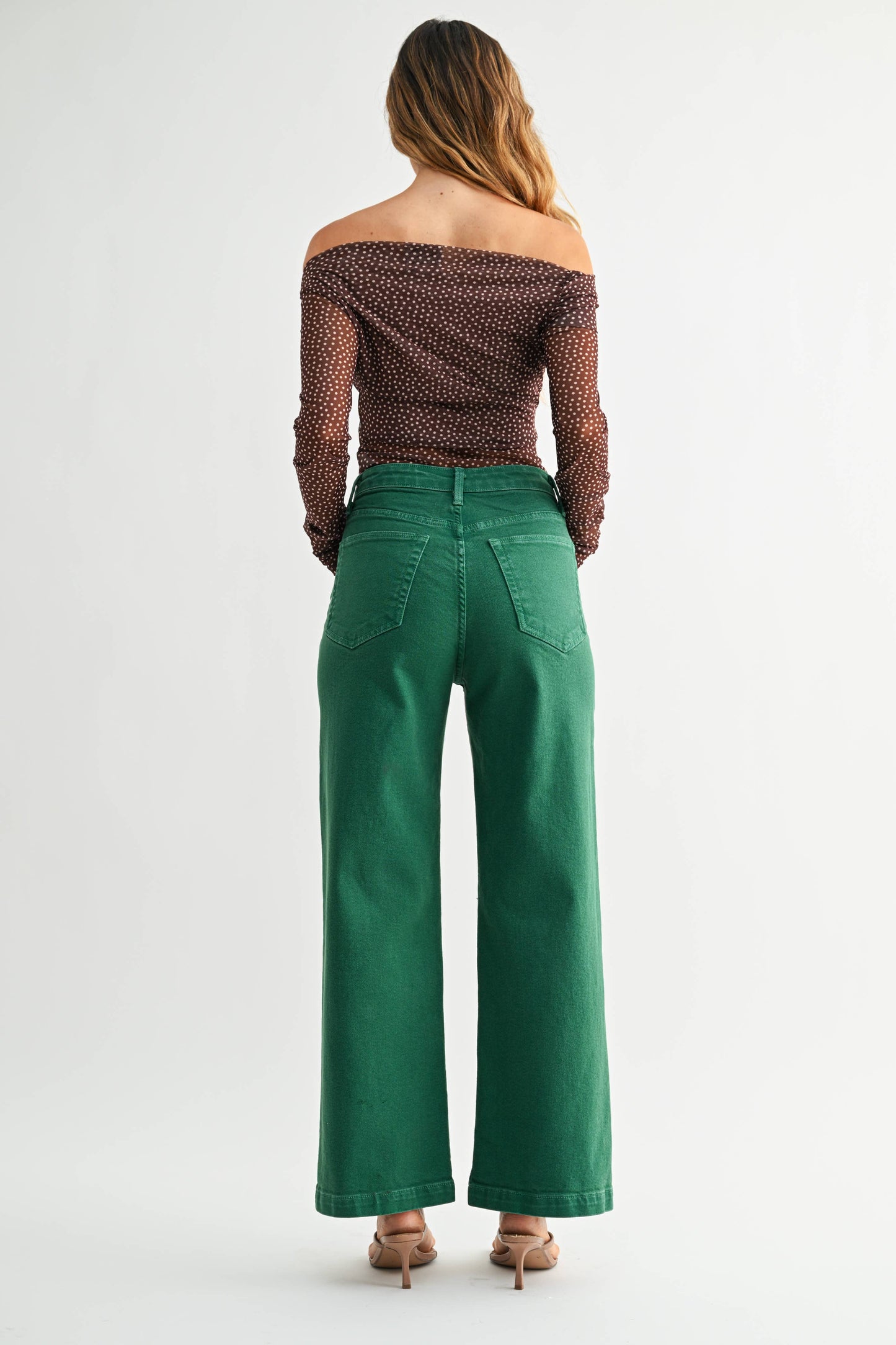 Woman wearing green pants and a patterned top on a white background