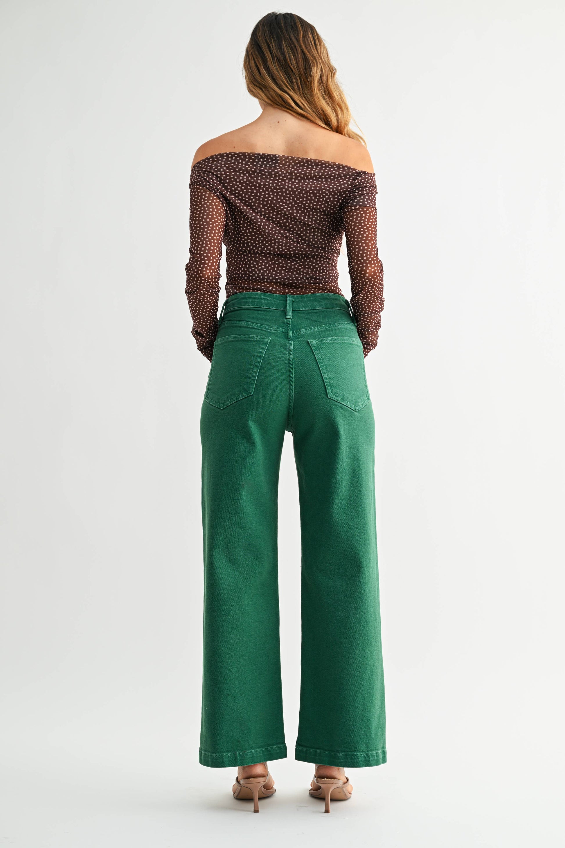 Woman wearing green pants and a patterned top on a white background