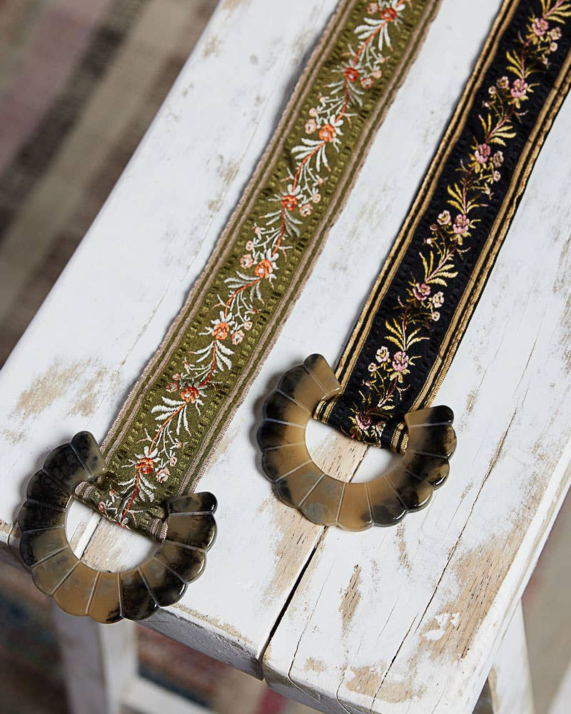 Decorative belt with floral embroidery on a rustic wooden surface