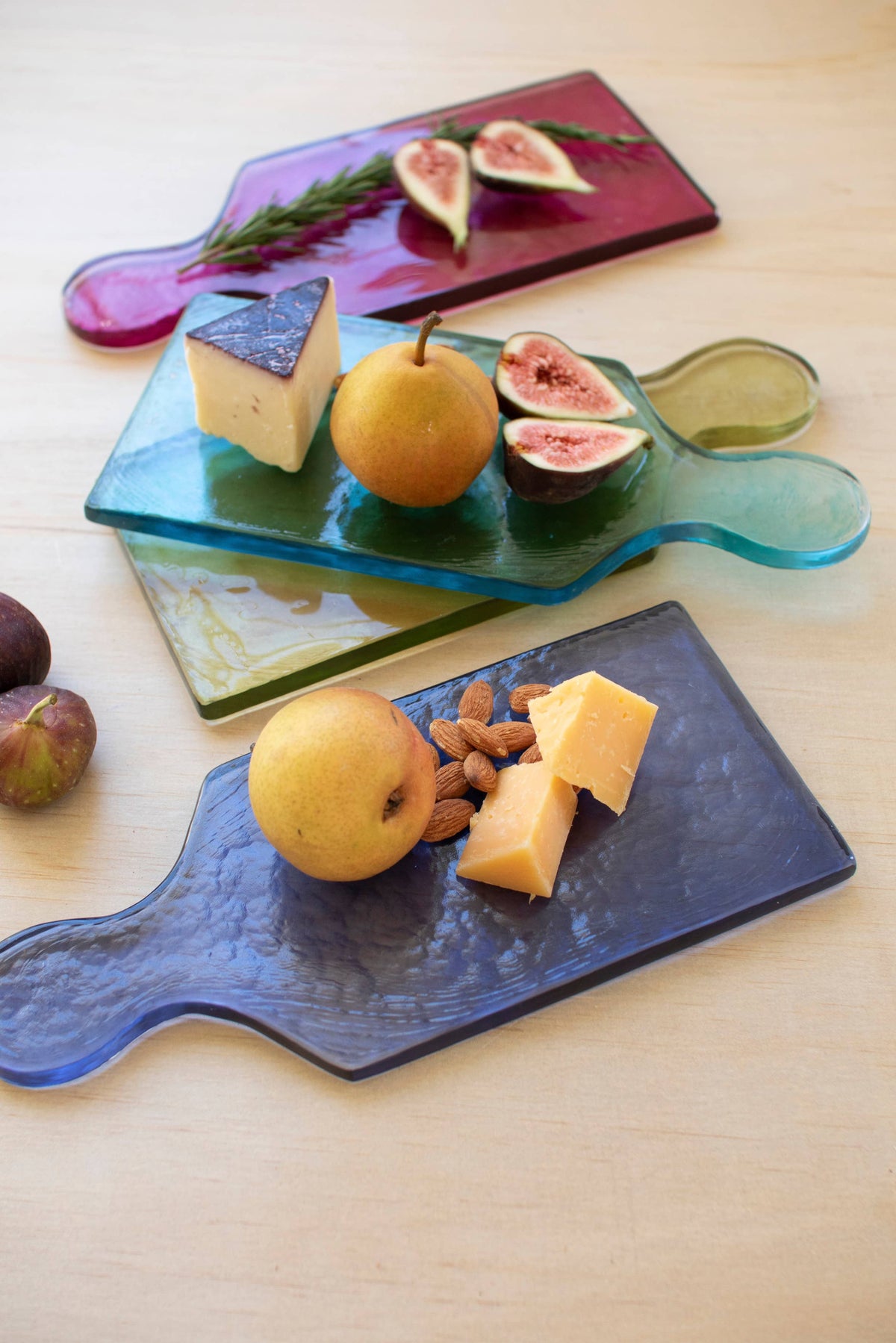 Glass cutting boards with fruit and cheese on a wooden surface