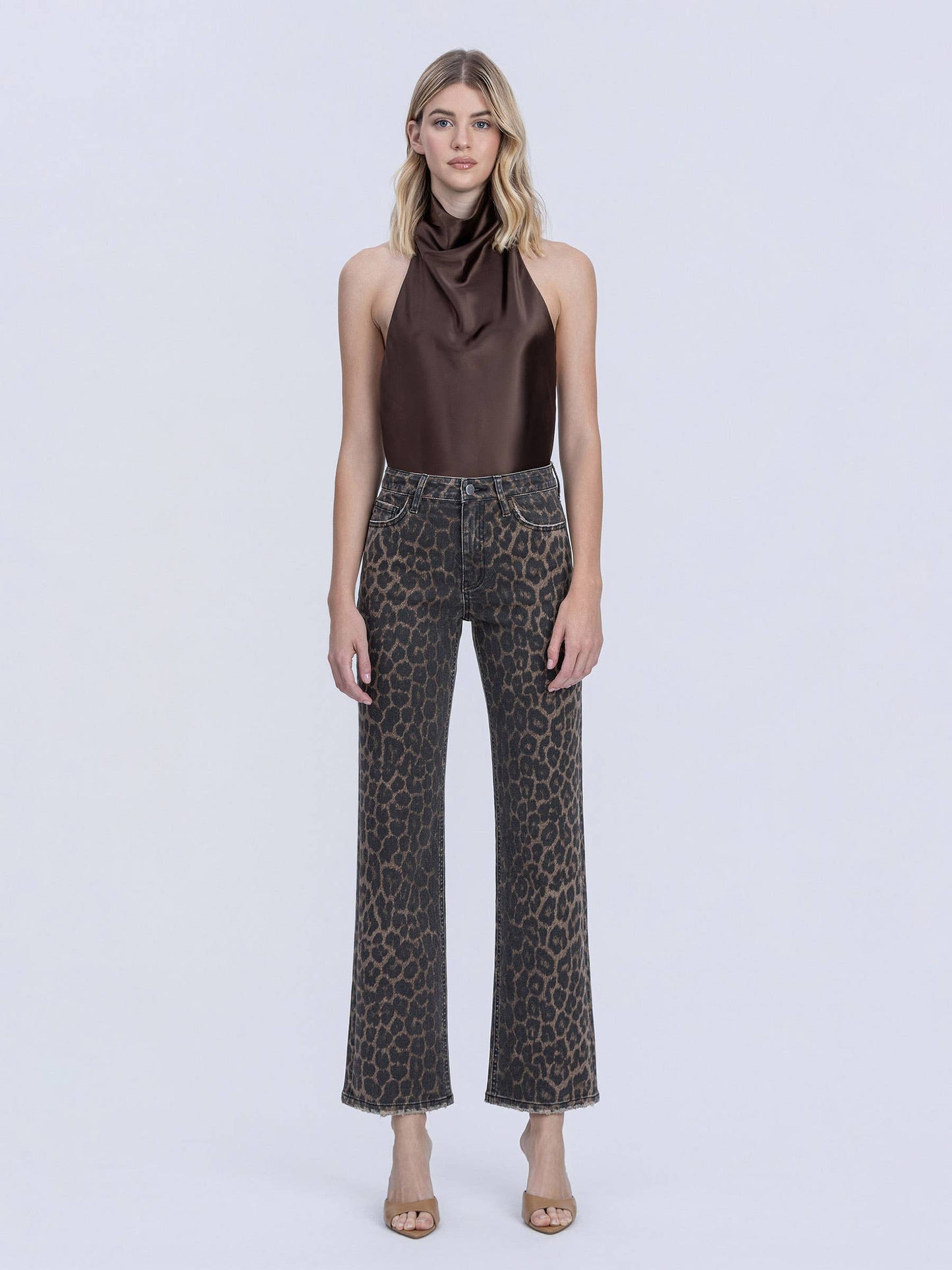 Woman wearing a brown halter top and leopard print pants on a white background