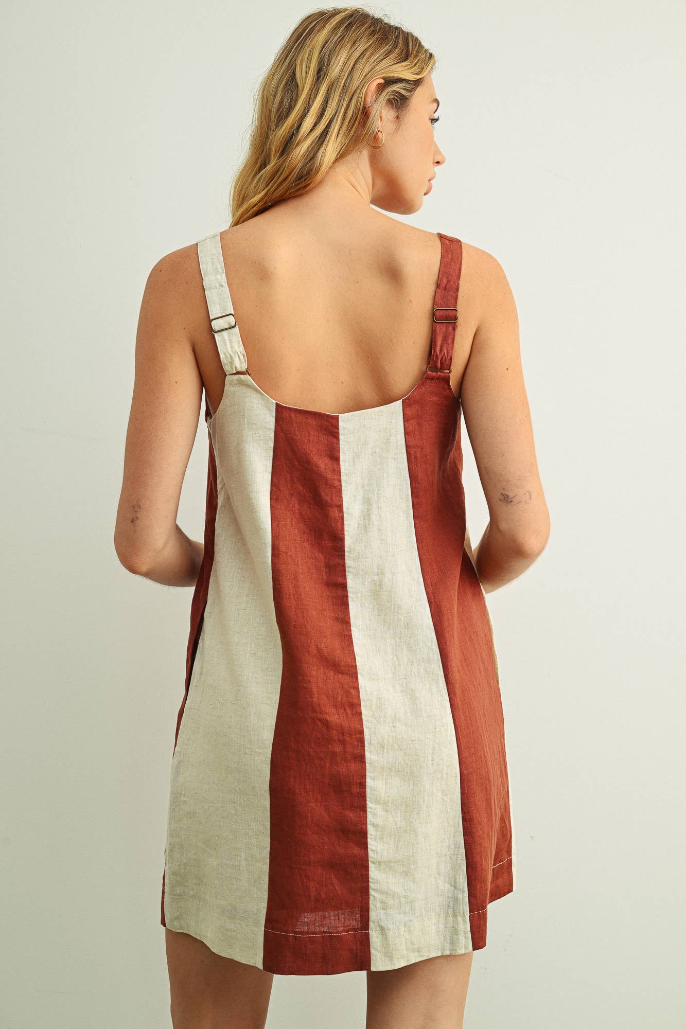 Woman wearing a red and white dress with thin straps on a plain background
