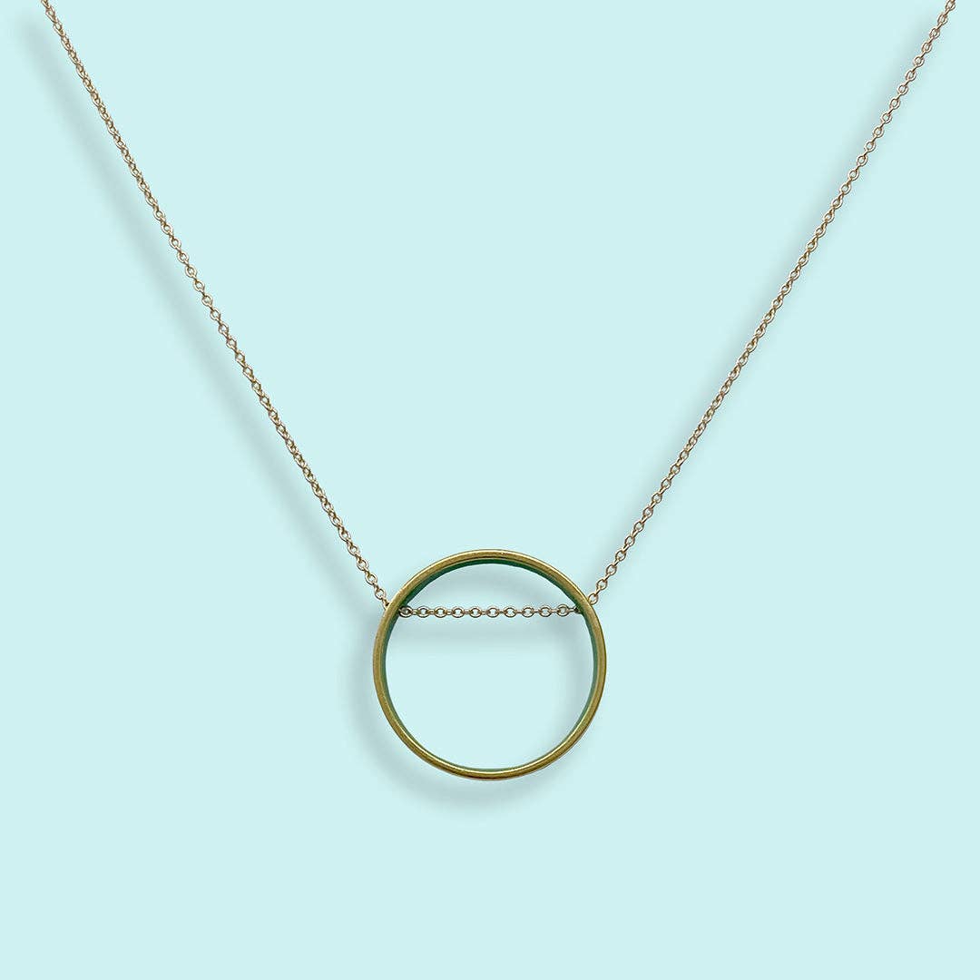 Gold circle pendant necklace on a light blue background