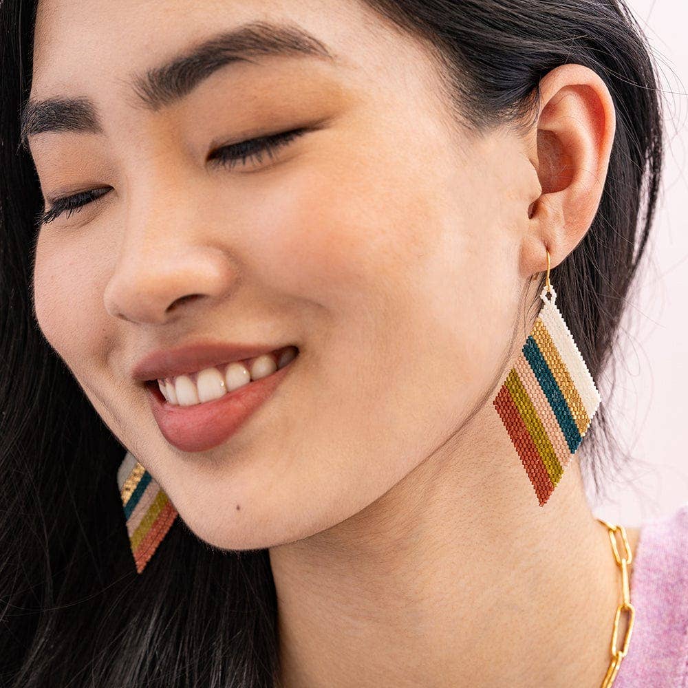 Close-up of a woman wearing colorful geometric earrings.
