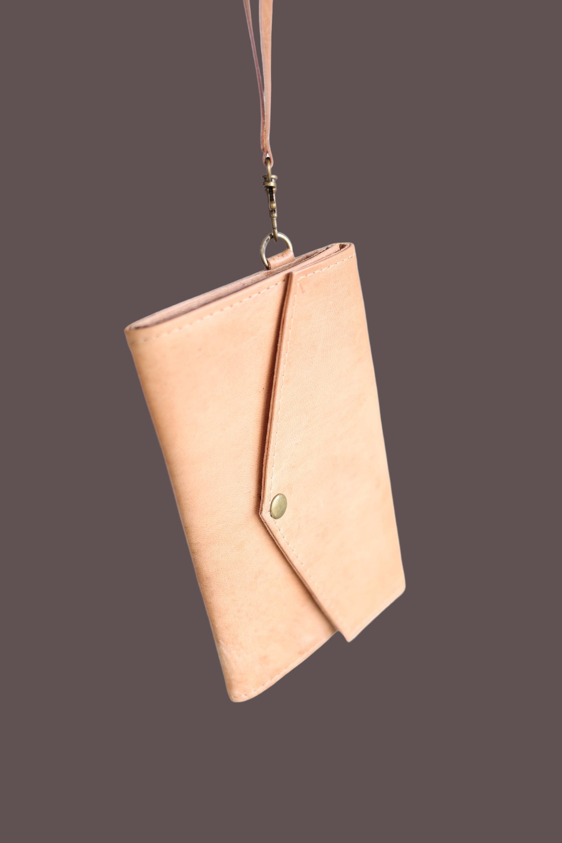 Tan envelope clutch with a strap on a white background